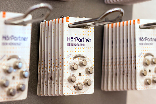 Hörgerätebatterien von HörPartner in Blisterverpackung hängen an einer Wand im Geschäft.